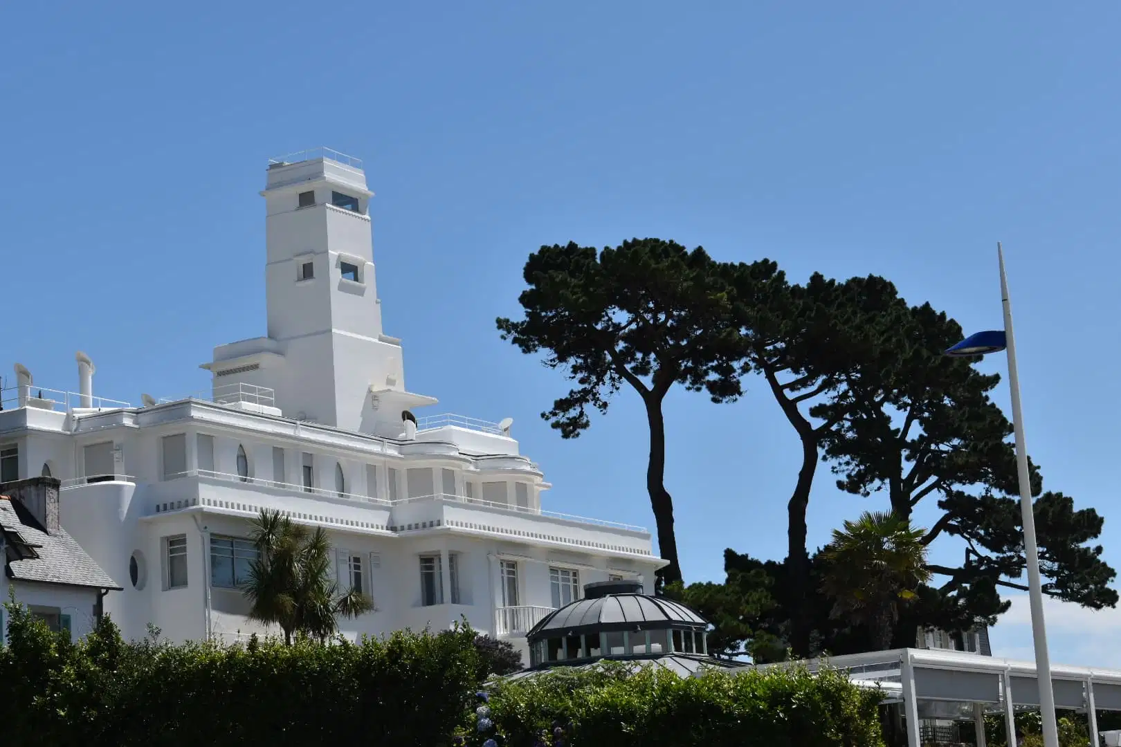 Bâtiment blanc avec une tour, entouré de pins et de palmiers