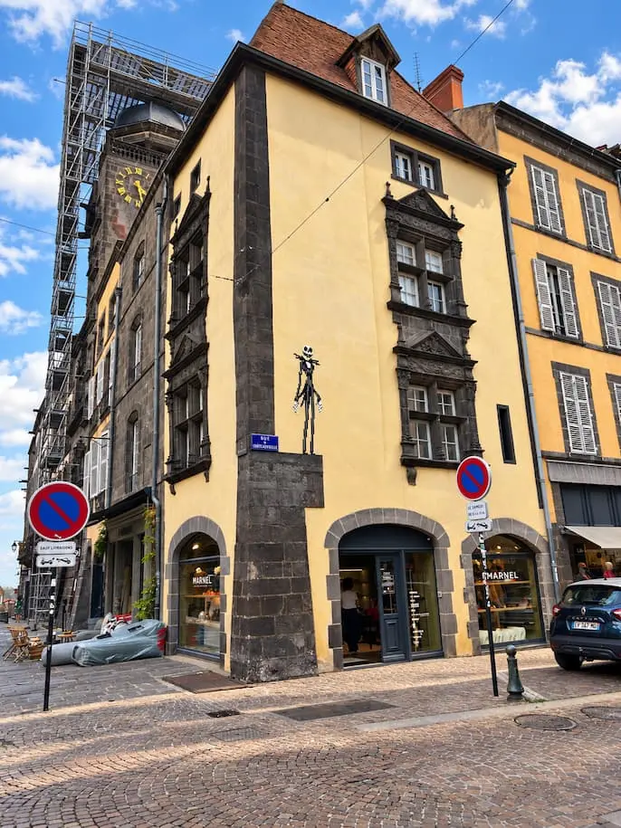 Maison ancienne à façade jaune et encadrements en pierre sombre à Riom